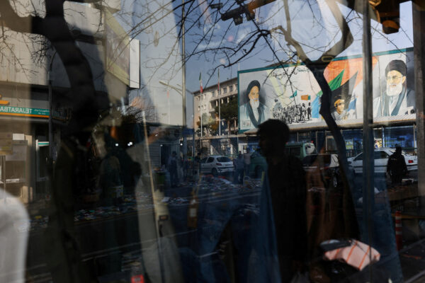 A sign with a depiction of Iran’s Supreme Leader, Ayatollah Ali Khamenei, is reflected in a shop window in Tehran