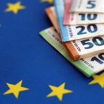 European eur currency money bills on Euro union blue flag close up