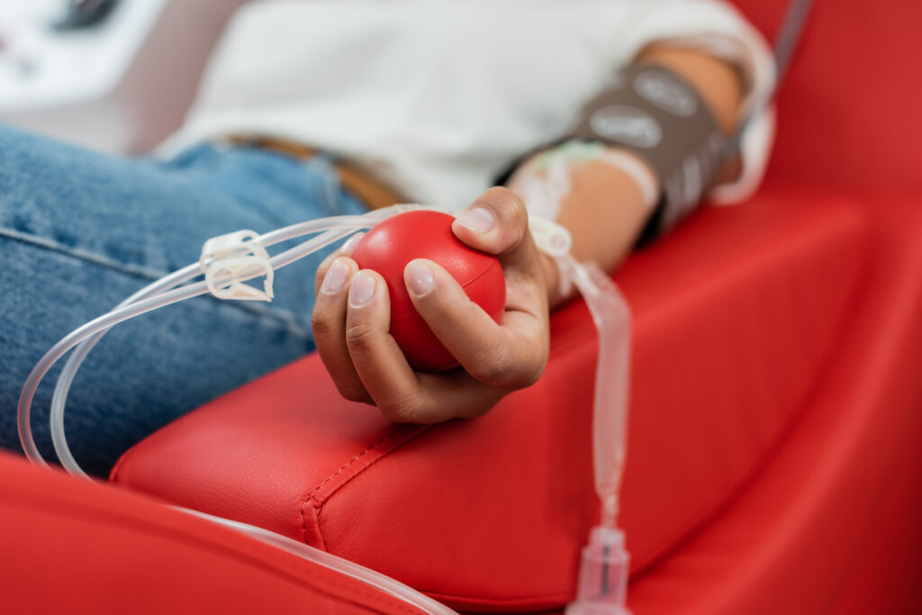 selective focus of rubber ball in hand of multiracial woman with transfusion set sitting on