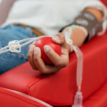 selective focus of rubber ball in hand of multiracial woman with transfusion set sitting on