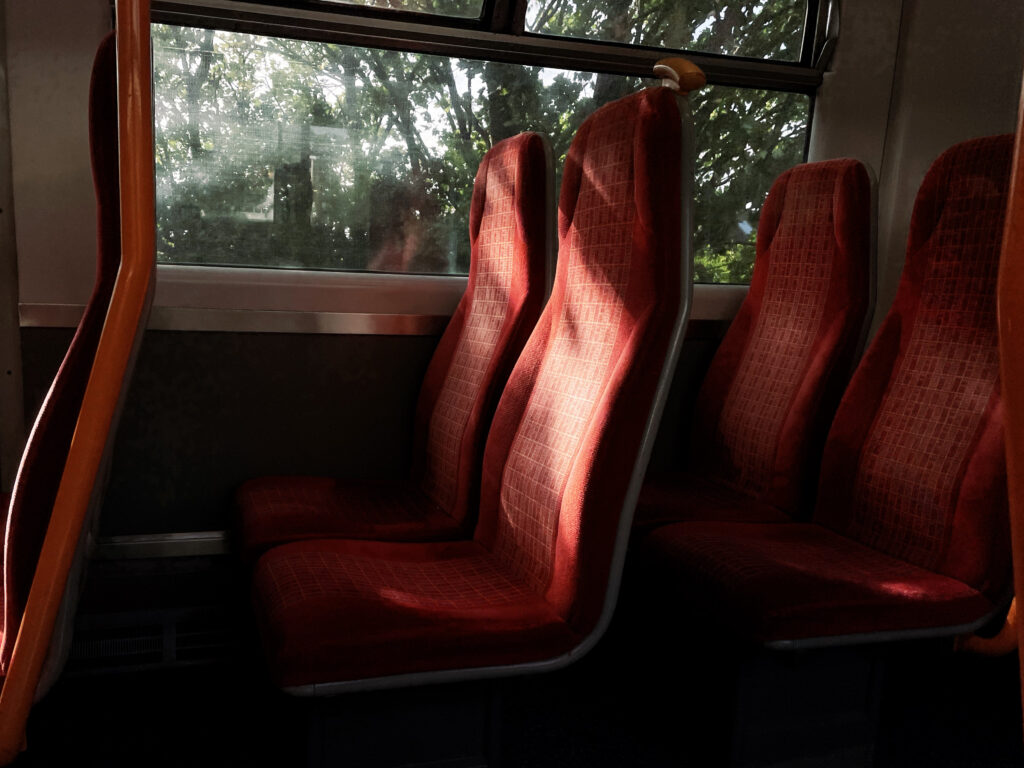 Train interior with two red rows of empty seats and sunlight