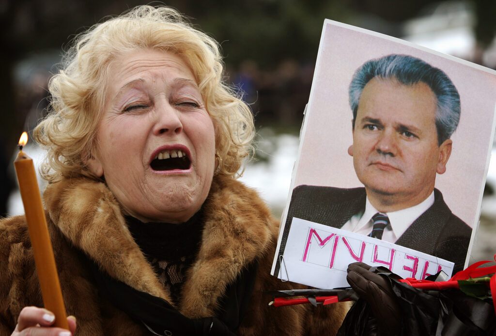 A supporter of Slobodan Milosevic grieves and holds a picture of the former Serbian president while waiting to enter the Museum of the Revolution where the coffin with his body is displayed in Belgrade