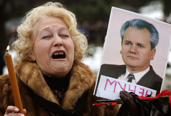 A supporter of Slobodan Milosevic grieves and holds a picture of the former Serbian president while waiting to enter the Museum of the Revolution where the coffin with his body is displayed in Belgrade