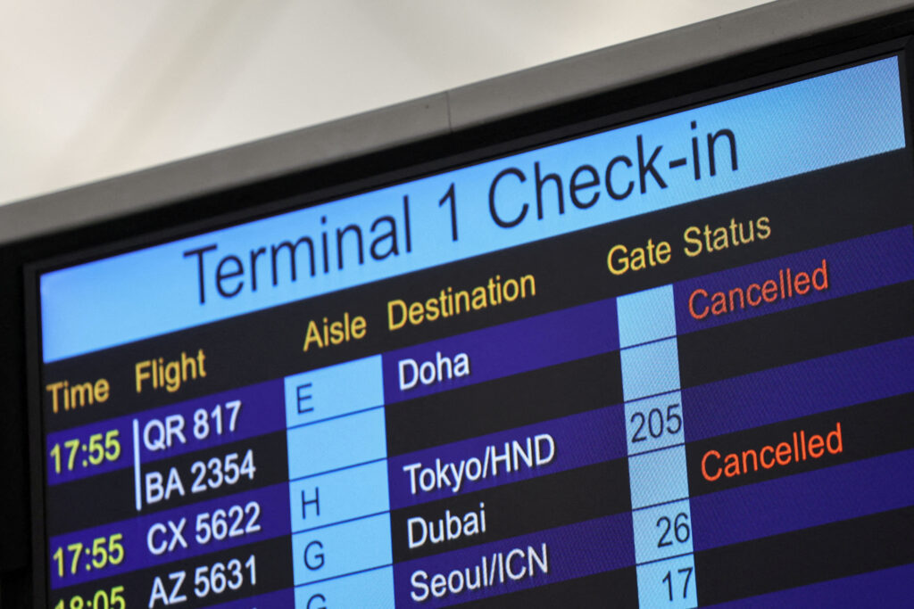 A screen displays cancelled flights to Middle East destinations at the Hong Kong International Airport