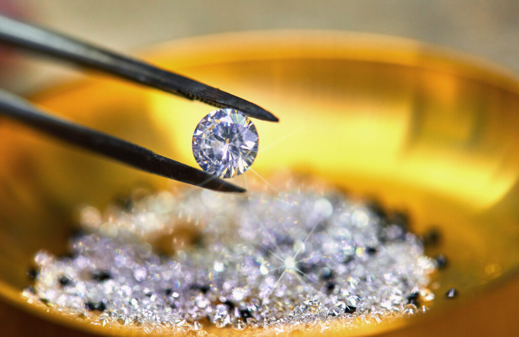 Diamond held by tweezers against the background