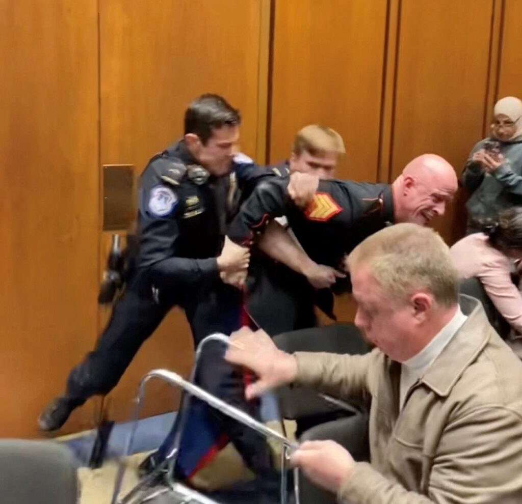 Former Marine Sgt. Brian McGuinness is dragged out during the Senate Armed Services subcommittee hearing, in Washington