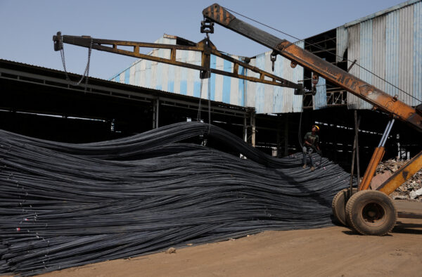 FILE PHOTO: A labourer unloads TMT steel bars from a crane inside a steel bar manufacturing factory at Viramgam