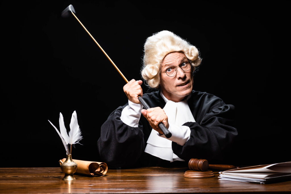 angry judge in judicial robe and wig holding golf club isolated on black