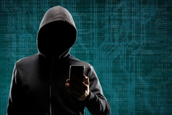 hooded-person-holding-phone-against-a-binary-code-2026-03-26-06-06-12-utc