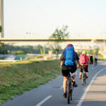 Sportive couple cycling by Ada Bridge over the Sava river in Belgrade, Serbia, on hot summer day. Nice sport for active people. Healthy lifestyle.