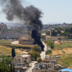 Black smoke billows at a strike scene following an Israeli strike on a car as seen from Nabatieh