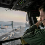 A naval officer aboard USS Tripoli (LHA 7) oversees flight operations