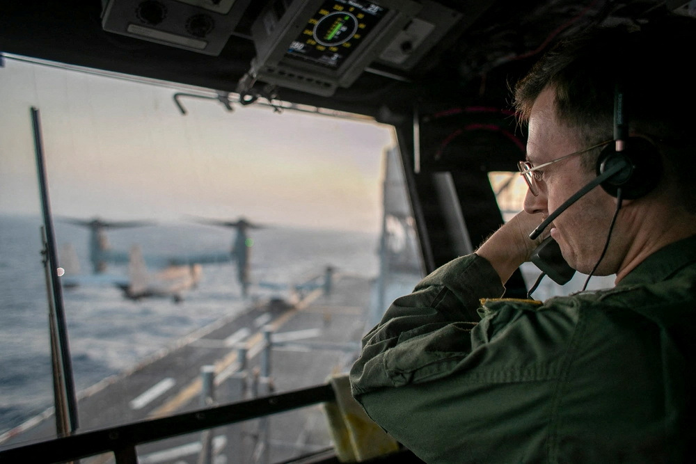 A naval officer aboard USS Tripoli (LHA 7) oversees flight operations