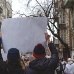 Two people holding poster in hands against background of feminist protest.