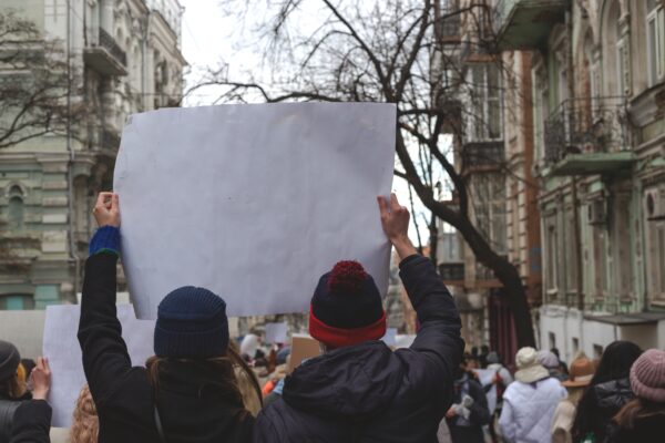 Two people holding poster in hands against background of feminist protest.