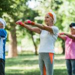 selective focus of senior pensioners exercising with dumbbells in park