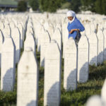 A woman walks among graves in Memorial Center Potocari, near Srebrenica