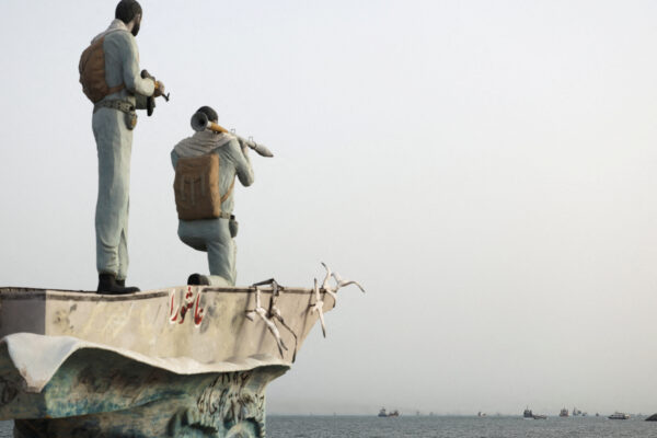 FILE PHOTO: A statue of Iranian military members stands as vessels in the Strait of Hormuz are visible near the beach of Bandar Abbas