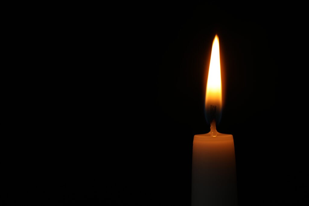 Burning candle on dark background, space for text. Symbol of sorrow