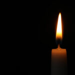 Burning candle on dark background, space for text. Symbol of sorrow