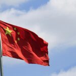 Chinese flag attached to a pole under a blue sky in the wind