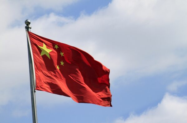 Chinese flag attached to a pole under a blue sky in the wind
