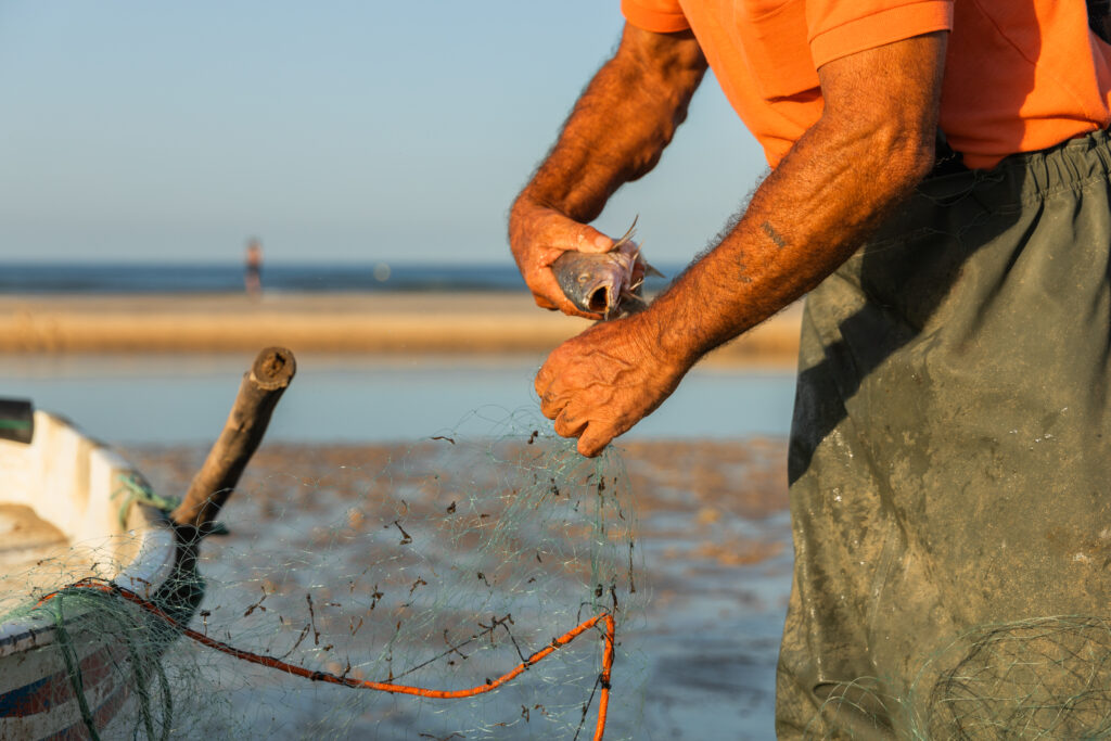 Unrecognizable man tying strings of fishing net