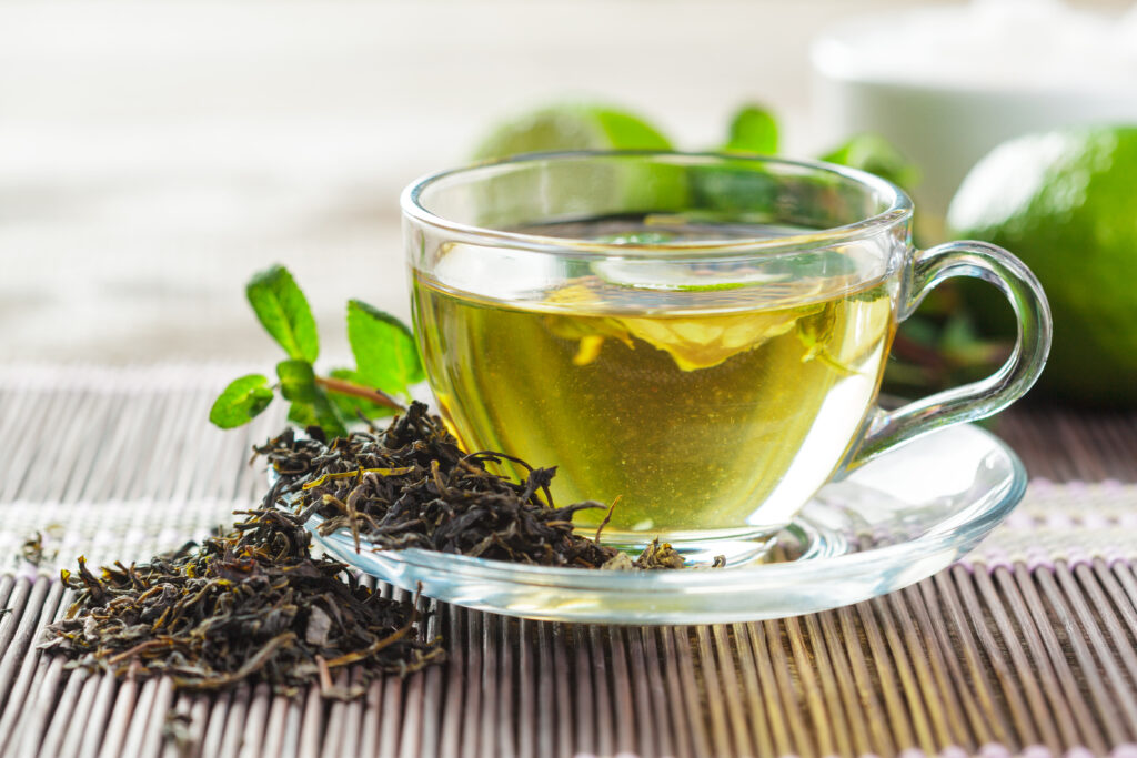 Green tea in glass cup with leaves and lime on wooden table
