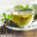 Green tea in glass cup with leaves and lime on wooden table