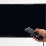 Black man watching TV and using remote controller
