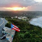 Aerial shot of the Flag of Puerto Rico waving in the air at a golden sunset in Quebradillas