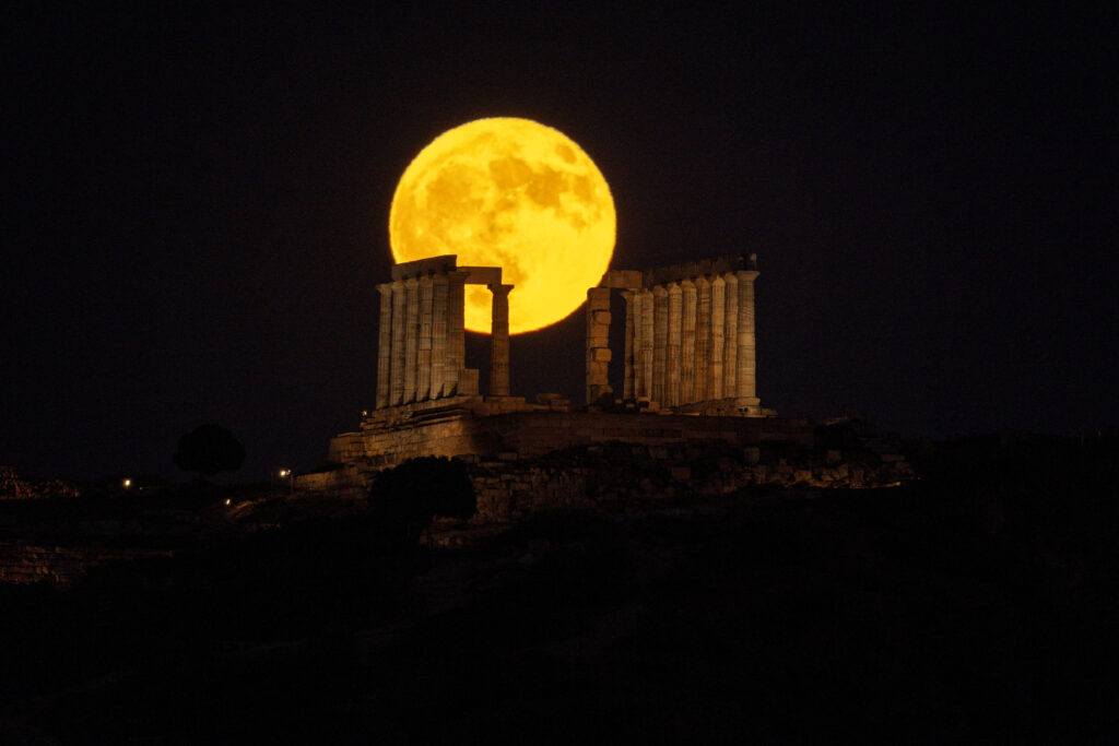 Buck full moon rises over the Poseidon Temple in Sounion, Greece