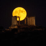 Buck full moon rises over the Poseidon Temple in Sounion, Greece