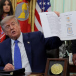 U.S. President Donald Trump signs an executive order in the Oval Office at the White House in Washington