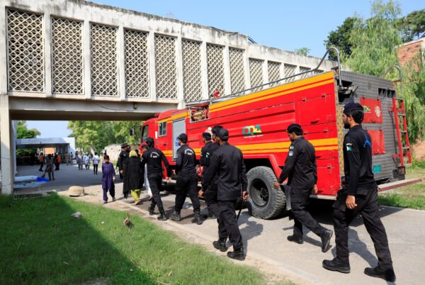 Members of Anti-Terrorist Squad move past a fire engine following a deadly fire at the PIMS hospital in Islamabad