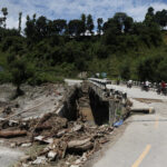 An auto rickshaw drives past a broken bridge following a flash flood in Galchhi