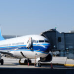 Airplane parked at terminal gate ready for boarding with bright blue accents during daytime at the airport