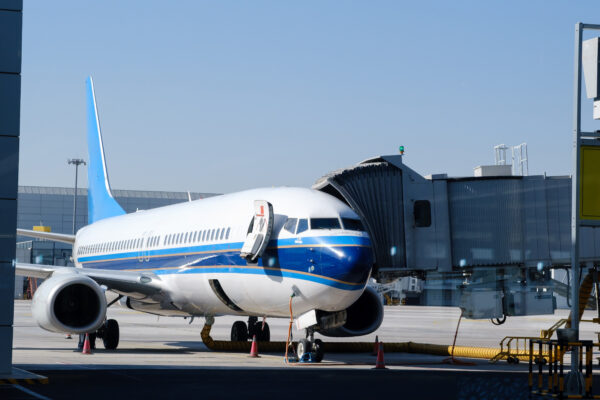 Airplane parked at terminal gate ready for boarding with bright blue accents during daytime at the airport