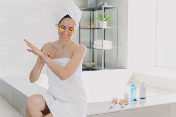 Lady applies eye patches and moisturizing skin with lotion. Relaxation at spa resort.