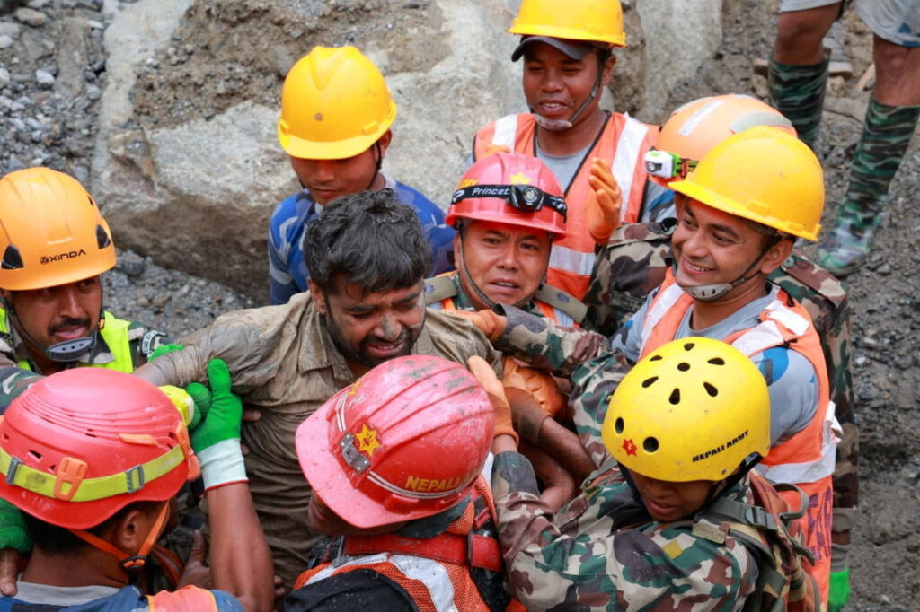 Survivor Sanjay Sah carried by members of a search and rescue team after they rescued alive two people who had been trapped inside a tunnel at the Upper Trishuli-3A Hydropower Project