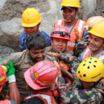 Survivor Sanjay Sah carried by members of a search and rescue team after they rescued alive two people who had been trapped inside a tunnel at the Upper Trishuli-3A Hydropower Project