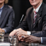 Hands of Black Man Sitting at Table while Speaking at Political Meeting