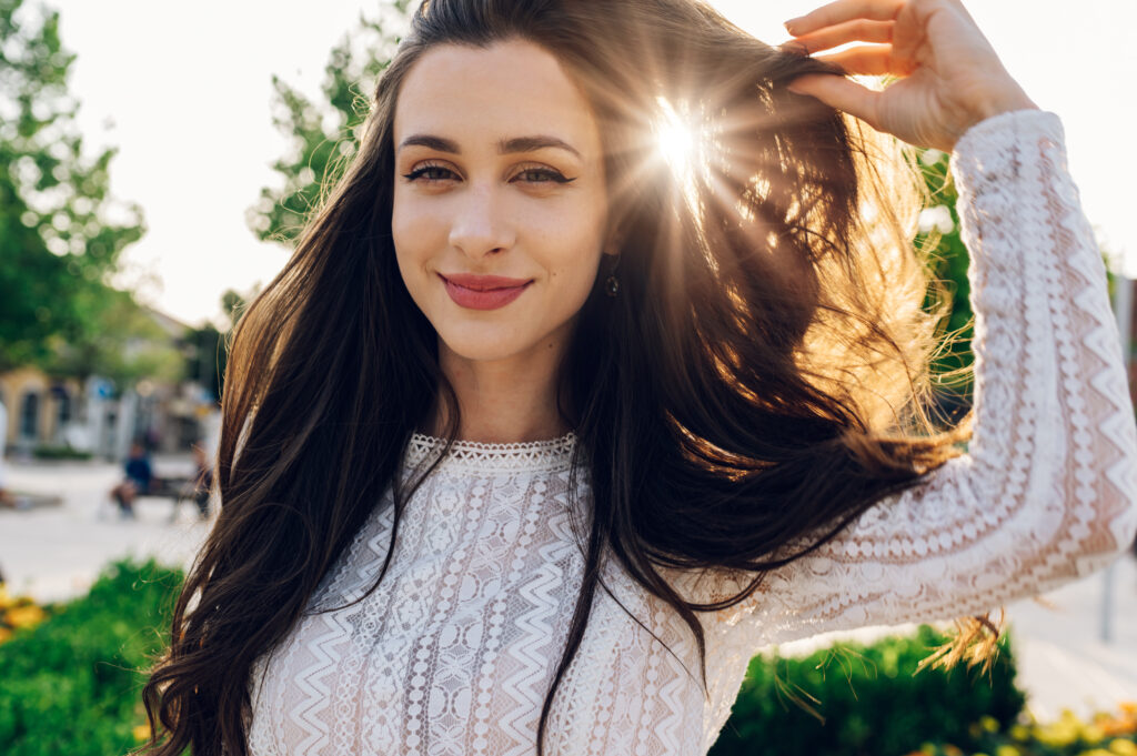 Portrait of a boho brunette posing outside and adjusting her hai