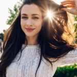 Portrait of a boho brunette posing outside and adjusting her hai